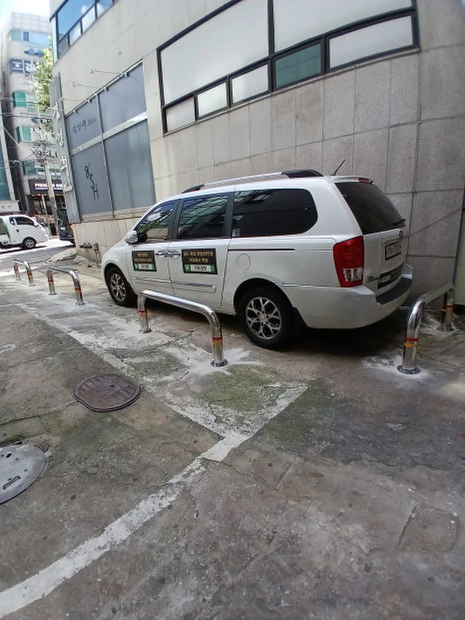 건물 모서리 도로변에 짧은 스테인리스 볼라드를 열로 설치한 모습