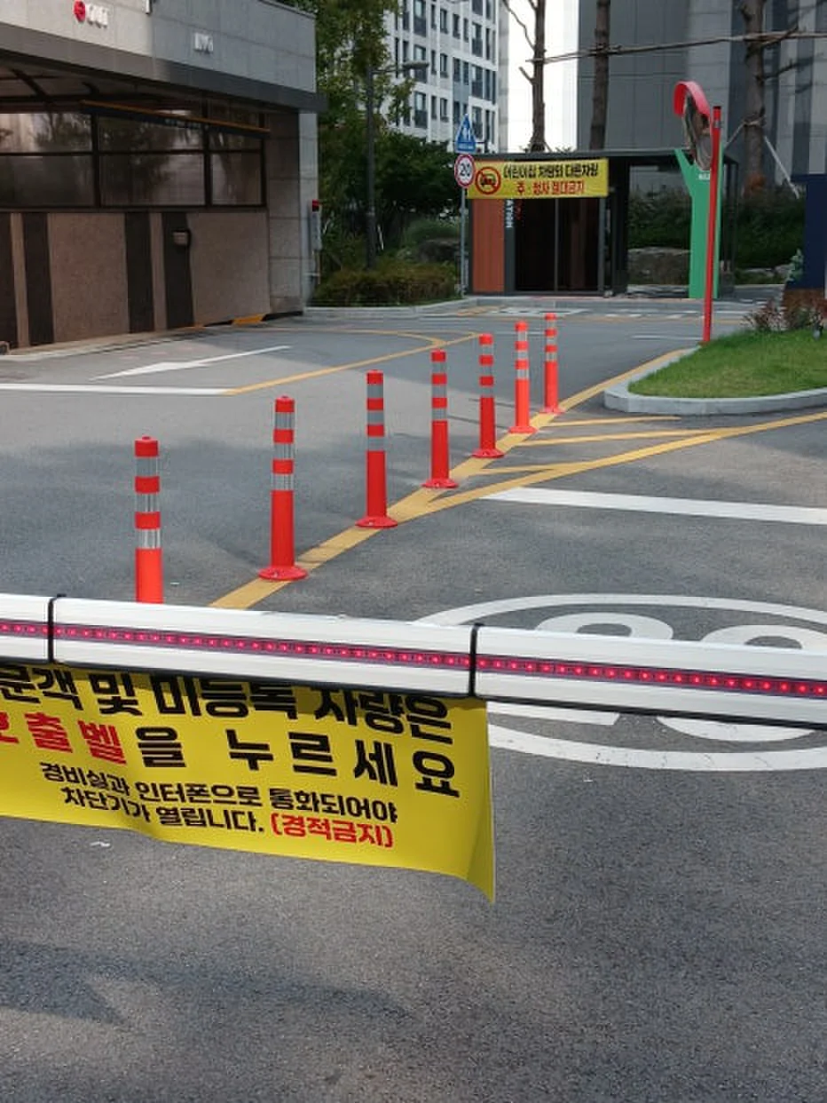 아파트 진입로 주황색 탄성 볼라드 열과 차단기 바 설치 현장
